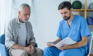 Older male patient discussing erectile dysfunction treatment options with a healthcare provider during a private clinic consultation.